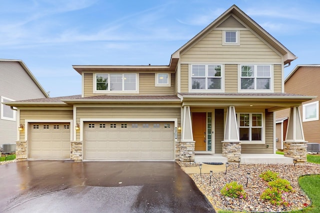 11330 Harness Rd, Woodbury, MN 55129 - view of front facade with a porch, asphalt driveway, stone siding, central AC, and an attached garage