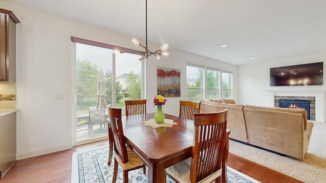 11330 Harness Rd, Woodbury, MN 55129 - dining space featuring light wood-style floors, a chandelier, a fireplace, baseboards, and recessed lighting
