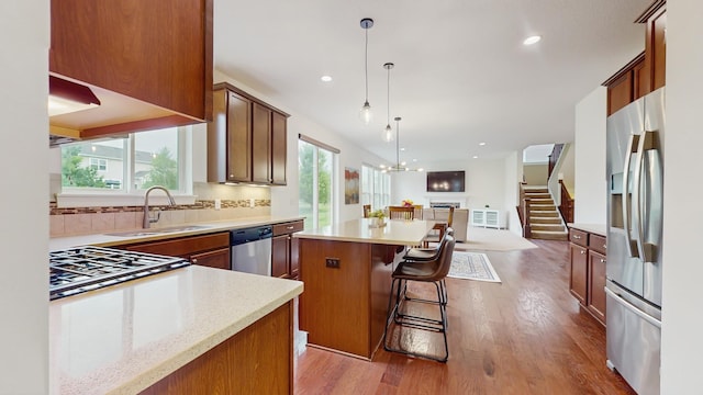 11330 Harness Rd, Woodbury, MN 55129 - kitchen with appliances with stainless steel finishes, a sink, open floor plan, a kitchen island, and wood finished floors