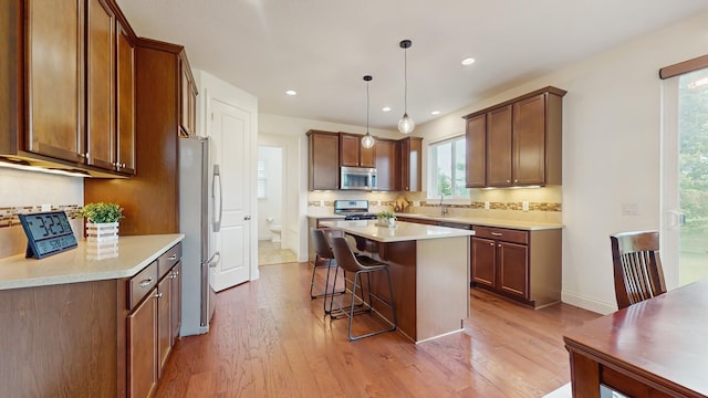 11330 Harness Rd, Woodbury, MN 55129 - kitchen featuring appliances with stainless steel finishes, a sink, backsplash, a kitchen breakfast bar, and a center island