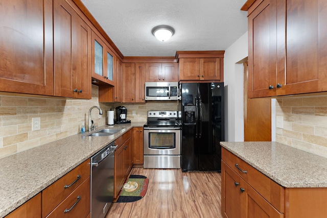 1533 Roundhouse Cir, Shakopee, MN 55379 - kitchen with stainless steel appliances, a sink, backsplash, brown cabinets, and light stone countertops