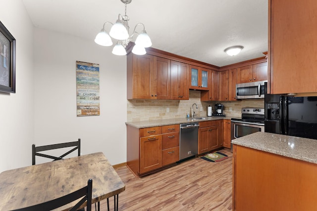 1533 Roundhouse Cir, Shakopee, MN 55379 - kitchen featuring appliances with stainless steel finishes, light wood finished floors, a chandelier, tasteful backsplash, and brown cabinetry