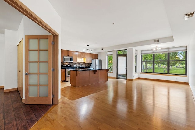 4500 Chicago Ave Unit 103, Minneapolis, MN 55407 - kitchen featuring appliances with stainless steel finishes, a chandelier, open floor plan, wood finished floors, and a kitchen breakfast bar
