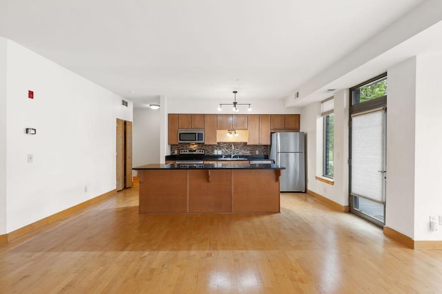 4500 Chicago Ave Unit 103, Minneapolis, MN 55407 - kitchen featuring appliances with stainless steel finishes, backsplash, light wood finished floors, baseboards, and brown cabinetry