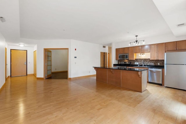 4500 Chicago Ave Unit 103, Minneapolis, MN 55407 - kitchen featuring appliances with stainless steel finishes, dark countertops, a chandelier, light wood-type flooring, and tasteful backsplash
