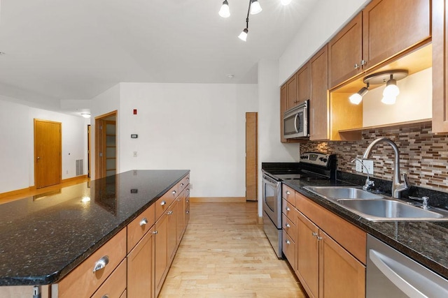 4500 Chicago Ave Unit 103, Minneapolis, MN 55407 - kitchen featuring stainless steel appliances, a sink, light wood finished floors, decorative backsplash, and brown cabinetry