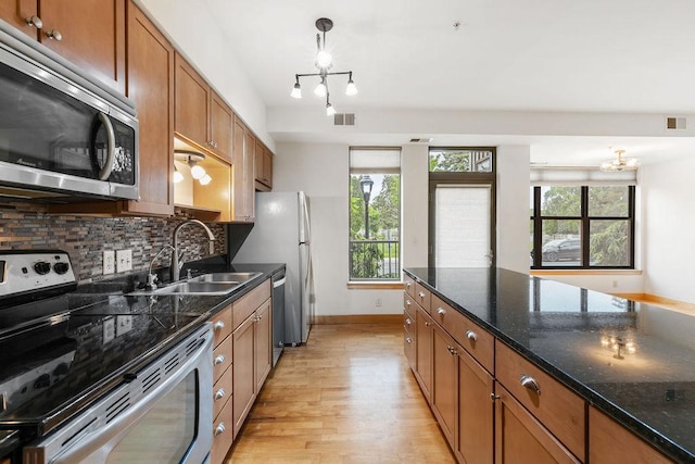 4500 Chicago Ave Unit 103, Minneapolis, MN 55407 - kitchen featuring appliances with stainless steel finishes, a sink, brown cabinetry, light wood-style flooring, and baseboards
