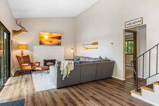 2625 7th Ave, Chetek, WI 54728 - living area featuring wood finished floors, stairs, a glass covered fireplace, a baseboard heating unit, and high vaulted ceiling