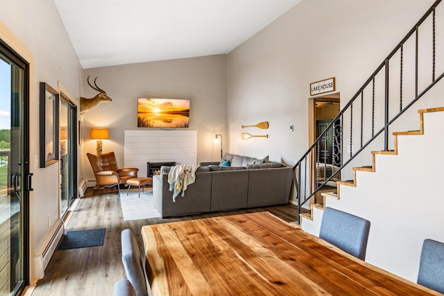2625 7th Ave, Chetek, WI 54728 - living area featuring lofted ceiling, wood finished floors, stairs, a baseboard radiator, and a lit fireplace