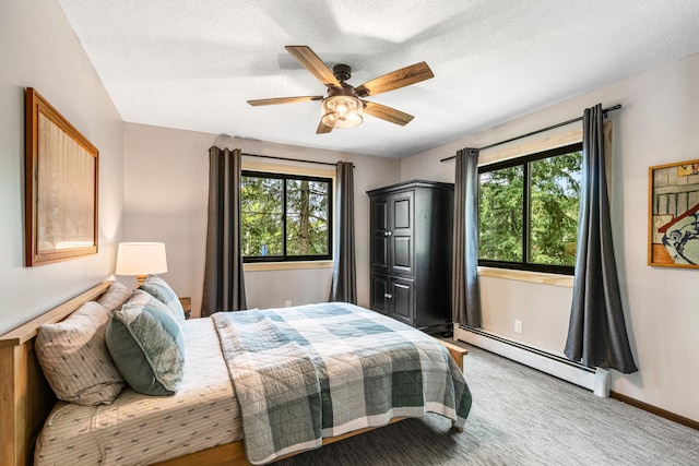 2625 7th Ave, Chetek, WI 54728 - carpeted bedroom featuring a baseboard heating unit, multiple windows, a ceiling fan, and baseboards