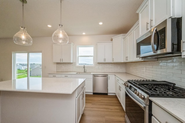 535 Rolling Hills Ln, Delano, MN 55328 - kitchen with appliances with stainless steel finishes, a center island, white cabinetry, tasteful backsplash, and light countertops