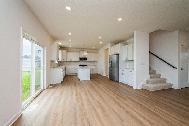 535 Rolling Hills Ln, Delano, MN 55328 - kitchen with stainless steel appliances, tasteful backsplash, a kitchen island, light wood-style floors, and white cabinetry