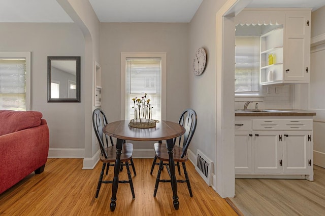 624 2nd St NE, Faribault, MN 55021 - dining area featuring light wood-style floors, plenty of natural light, baseboards, and arched walkways