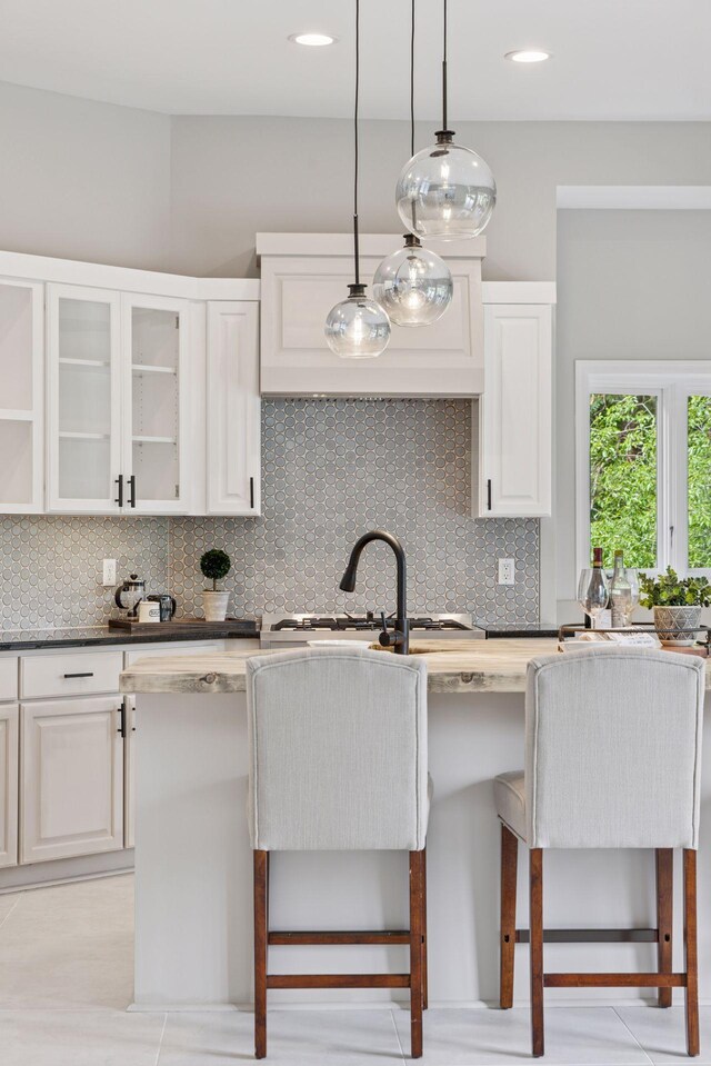 17032 Valley Dr NW, Andover, MN 55304 - kitchen with backsplash, a breakfast bar area, decorative light fixtures, glass insert cabinets, and white cabinets