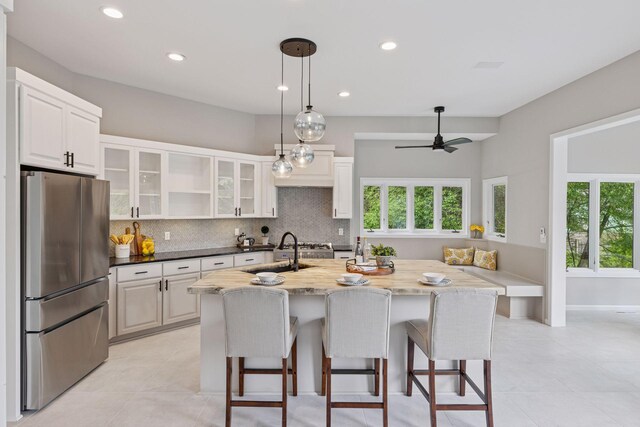 17032 Valley Dr NW, Andover, MN 55304 - kitchen with freestanding refrigerator, a sink, a kitchen bar, backsplash, and glass insert cabinets
