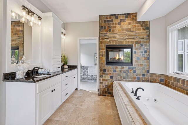 17032 Valley Dr NW, Andover, MN 55304 - full bathroom with a multi sided fireplace, connected bathroom, a whirlpool tub, vanity, and stone finish floors