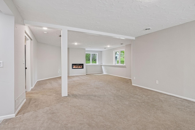 17032 Valley Dr NW, Andover, MN 55304 - unfurnished living room featuring a textured ceiling, carpet floors, baseboards, a glass covered fireplace, and recessed lighting