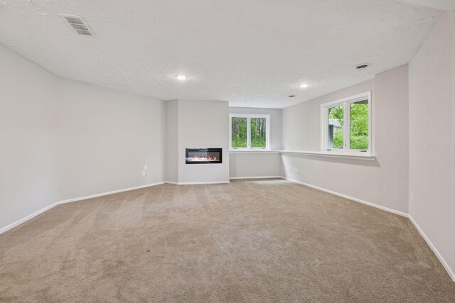 17032 Valley Dr NW, Andover, MN 55304 - unfurnished living room with carpet, baseboards, a textured ceiling, a glass covered fireplace, and recessed lighting