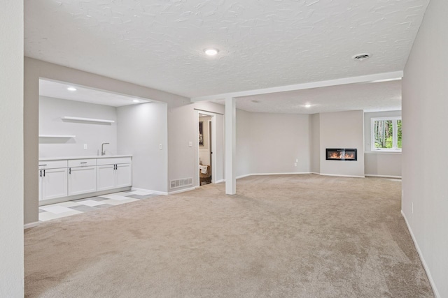 17032 Valley Dr NW, Andover, MN 55304 - unfurnished living room with light colored carpet, baseboards, recessed lighting, a glass covered fireplace, and a textured ceiling