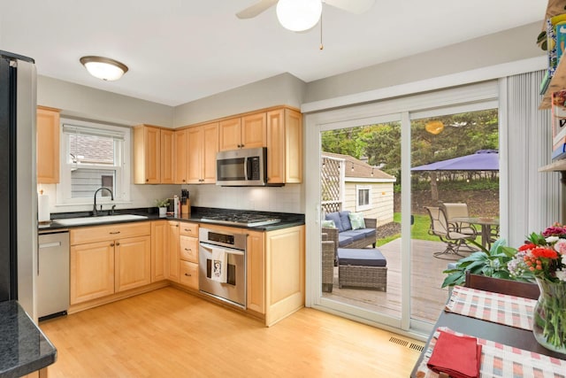 3350 Virginia Ave S, Saint Louis Park, MN 55426 - kitchen with stainless steel appliances, a sink, light brown cabinets, dark countertops, and light wood-type flooring