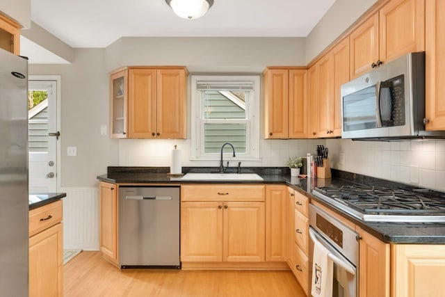 3350 Virginia Ave S, Saint Louis Park, MN 55426 - kitchen with stainless steel appliances, a sink, light wood-style flooring, light brown cabinets, and a wainscoted wall