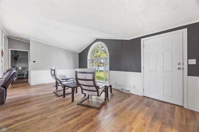3022 Sandy Beach Rd, Hatton, ND 58240 - dining area featuring wood finished floors, a wainscoted wall, a textured ceiling, vaulted ceiling, and ornamental molding
