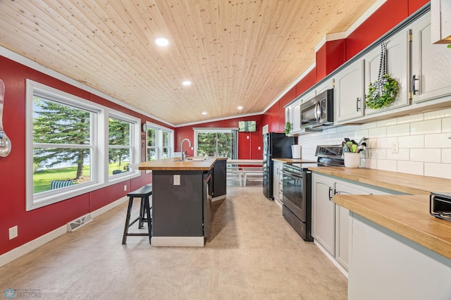 3022 Sandy Beach Rd, Hatton, ND 58240 - kitchen with wooden counters, appliances with stainless steel finishes, wooden ceiling, a center island with sink, and a kitchen breakfast bar