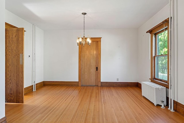 408 5th St E, Northfield, MN 55057 - spare room with radiator, light wood-style flooring, baseboards, and a chandelier
