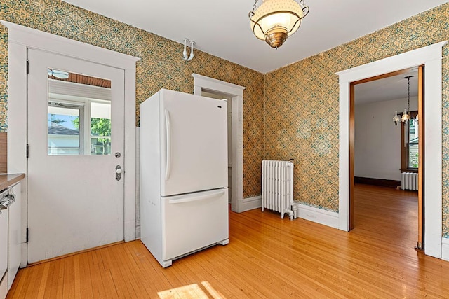 408 5th St E, Northfield, MN 55057 - kitchen featuring freestanding refrigerator, radiator heating unit, a chandelier, light wood finished floors, and wallpapered walls