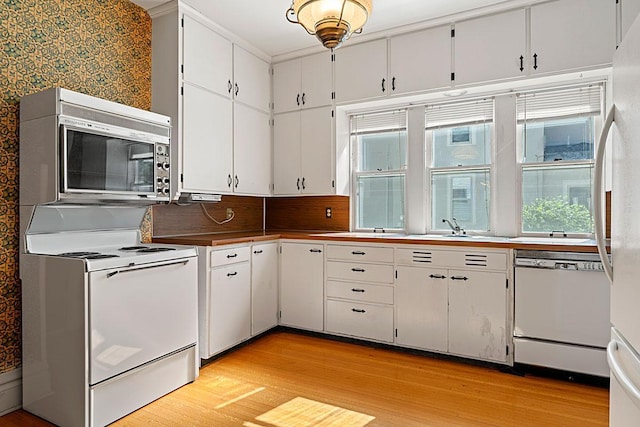 408 5th St E, Northfield, MN 55057 - kitchen with white appliances, light wood finished floors, white cabinets, wallpapered walls, and a sink