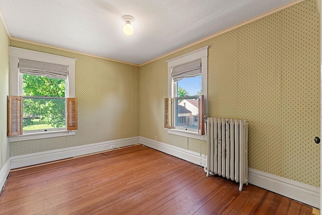 408 5th St E, Northfield, MN 55057 - empty room featuring radiator, ornamental molding, hardwood / wood-style flooring, baseboards, and wallpapered walls