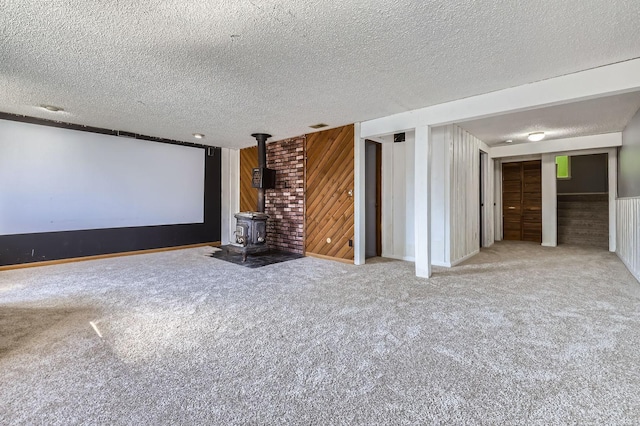 3944 76th Way E, Inver Grove Heights, MN 55076 - carpeted home theater featuring a wood stove, a textured ceiling, wood walls, and baseboards