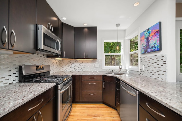 2934 Natchez Ave S, Saint Louis Park, MN 55416 - kitchen featuring stainless steel appliances, a sink, light stone counters, light wood-style floors, and backsplash