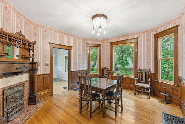 216 Summit Ave, Center City, MN 55012 - dining area with a wainscoted wall, wallpapered walls, light wood-style flooring, a chandelier, and a tile fireplace