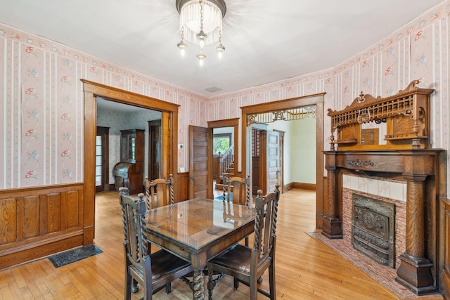 216 Summit Ave, Center City, MN 55012 - dining room with wallpapered walls, light wood-type flooring, wainscoting, a tile fireplace, and a chandelier