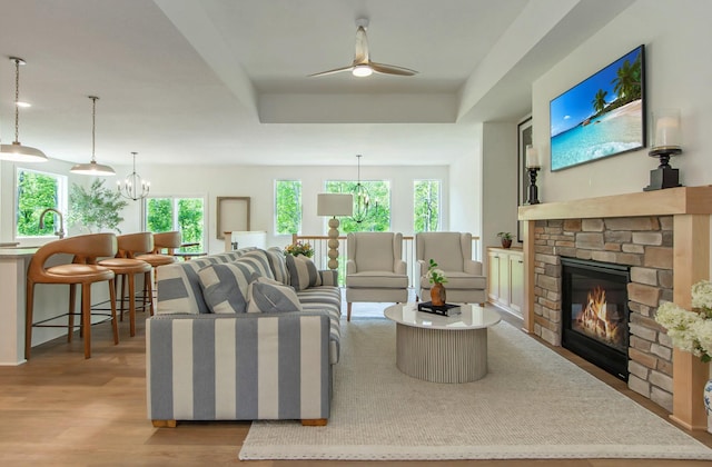 31709 Green Scene Dr, Breezy Point, MN 56472 - living room featuring a chandelier, a stone fireplace, light wood-style flooring, and ceiling fan