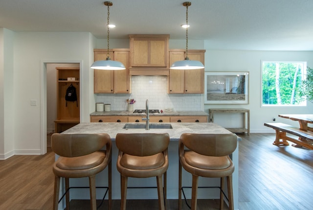 31709 Green Scene Dr, Breezy Point, MN 56472 - kitchen featuring backsplash, baseboards, dark wood-style floors, a kitchen island with sink, and light stone countertops