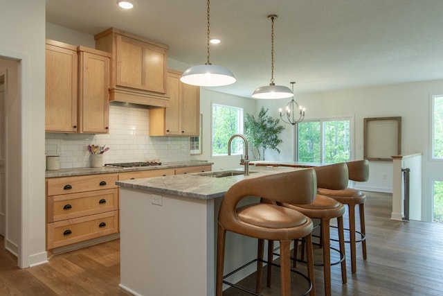 31709 Green Scene Dr, Breezy Point, MN 56472 - kitchen with a sink, wood finished floors, decorative backsplash, a kitchen island with sink, and a breakfast bar area