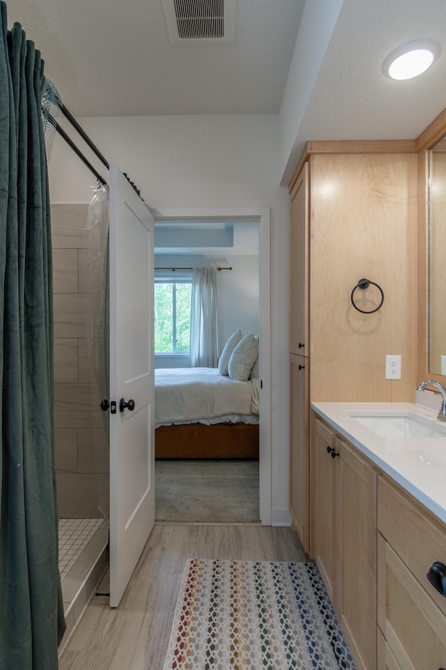 31709 Green Scene Dr, Breezy Point, MN 56472 - full bathroom featuring wood finished floors, vanity, tiled shower, and ensuite bathroom