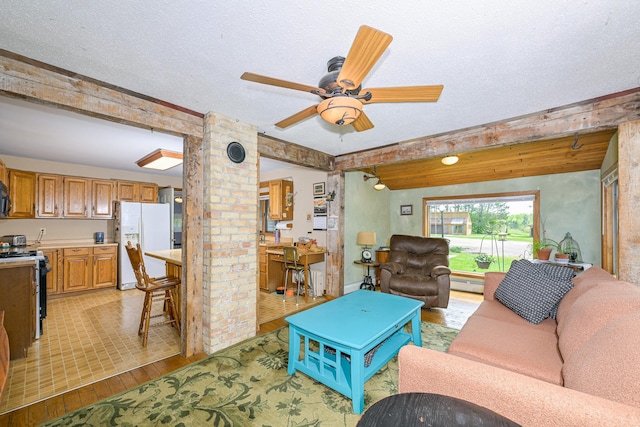 2444 County Rd 1, Wrenshall, MN 55797 - living area featuring light wood finished floors, a baseboard radiator, a ceiling fan, a textured ceiling, and ornate columns