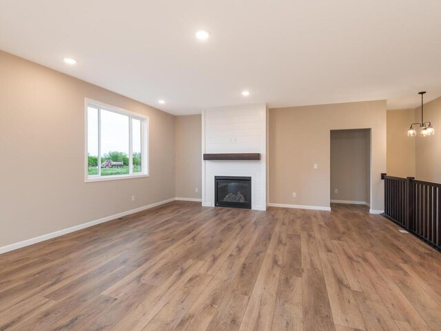 5393 177th St W, Lakeville, MN 55044 - unfurnished living room with wood finished floors, a fireplace, recessed lighting, baseboards, and a chandelier