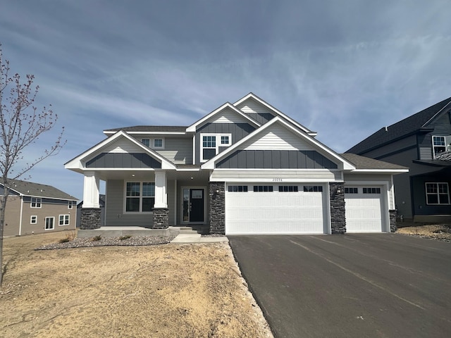 20098 67th Ave, Corcoran, MN 55340 - craftsman-style home with board and batten siding, stone siding, driveway, a garage, and covered porch