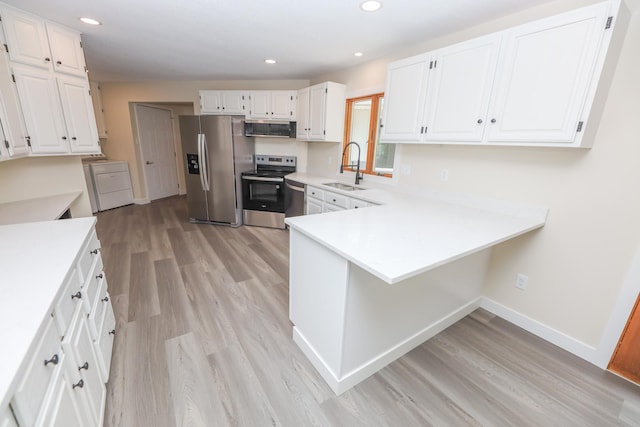 1202 Ridgeview Ter NE, Alexandria, MN 56308 - kitchen with stainless steel appliances, a sink, light wood finished floors, a peninsula, and white cabinetry