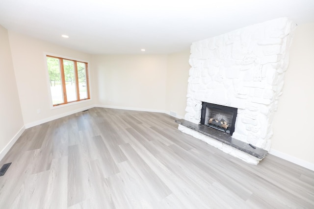 1202 Ridgeview Ter NE, Alexandria, MN 56308 - unfurnished living room featuring a stone fireplace, wood finished floors, baseboards, and recessed lighting
