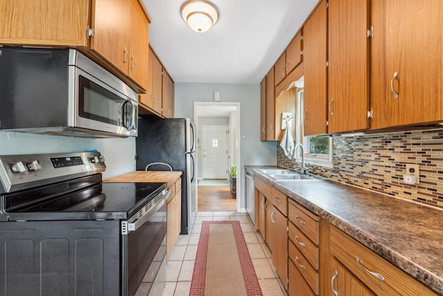 2918 Asbury St, Roseville, MN 55113 - kitchen featuring appliances with stainless steel finishes, a sink, decorative backsplash, light tile patterned floors, and brown cabinetry