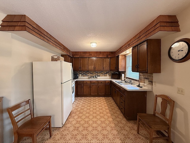 1646 5th St, Montevideo, MN 56265 - kitchen with freestanding refrigerator, light countertops, a textured ceiling, a sink, and tasteful backsplash