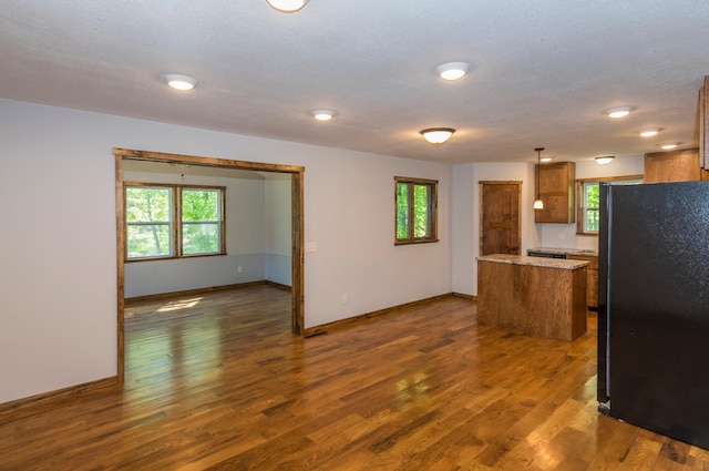 8296 Gladstone Lake Rd, Lake Edward Twp, MN 56401 - kitchen featuring freestanding refrigerator, brown cabinets, dark wood-style flooring, and healthy amount of natural light