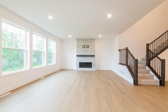 20117 63rd Ave, Corcoran, MN 55340 - unfurnished living room featuring light wood-style flooring, stairway, recessed lighting, and a stone fireplace