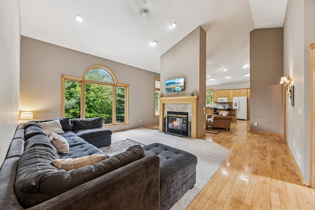 5160 202nd Ln NE, Linwood Twp, MN 55092 - living area featuring light wood-style flooring, a tile fireplace, high vaulted ceiling, baseboards, and recessed lighting