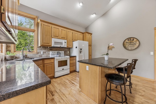 5160 202nd Ln NE, Linwood Twp, MN 55092 - kitchen featuring white appliances, a sink, a kitchen island, a kitchen bar, and light wood-type flooring